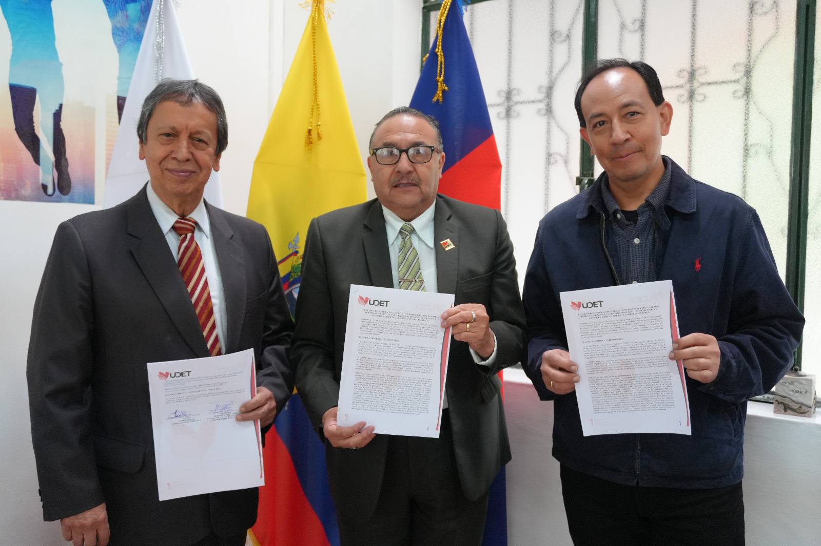 Three people holding signed documents