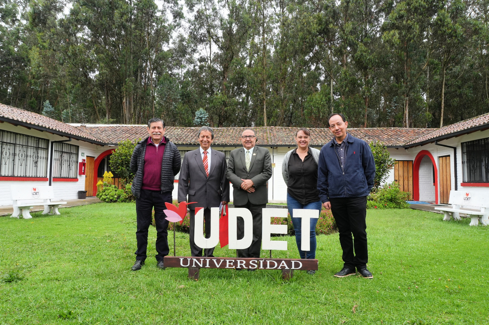 Five people stand by sign of University of Tourism Specialties of Ecuador