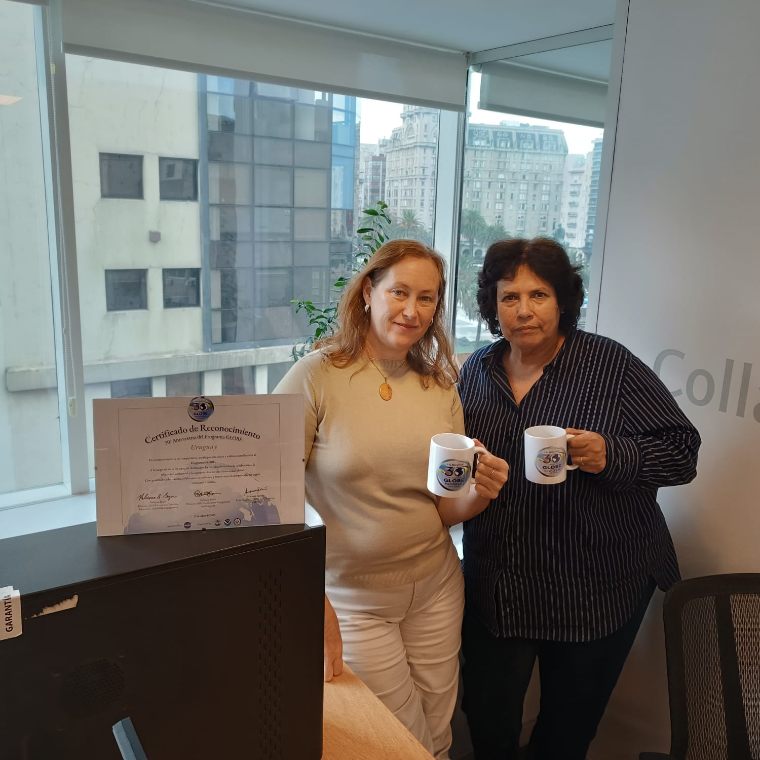 Two people with GLOBE anniversary certificate and mugs.