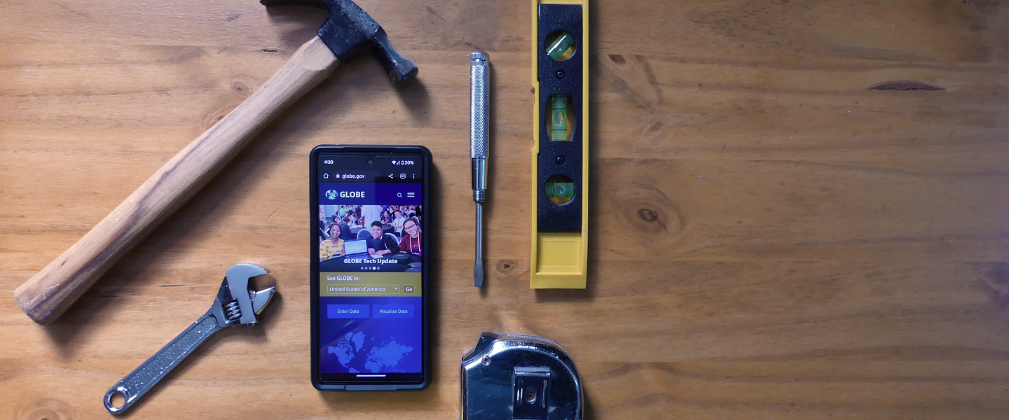 Tools surround a phone displaying a website on screen.