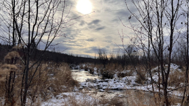 Sun glow through clouds reflecting on icy creek