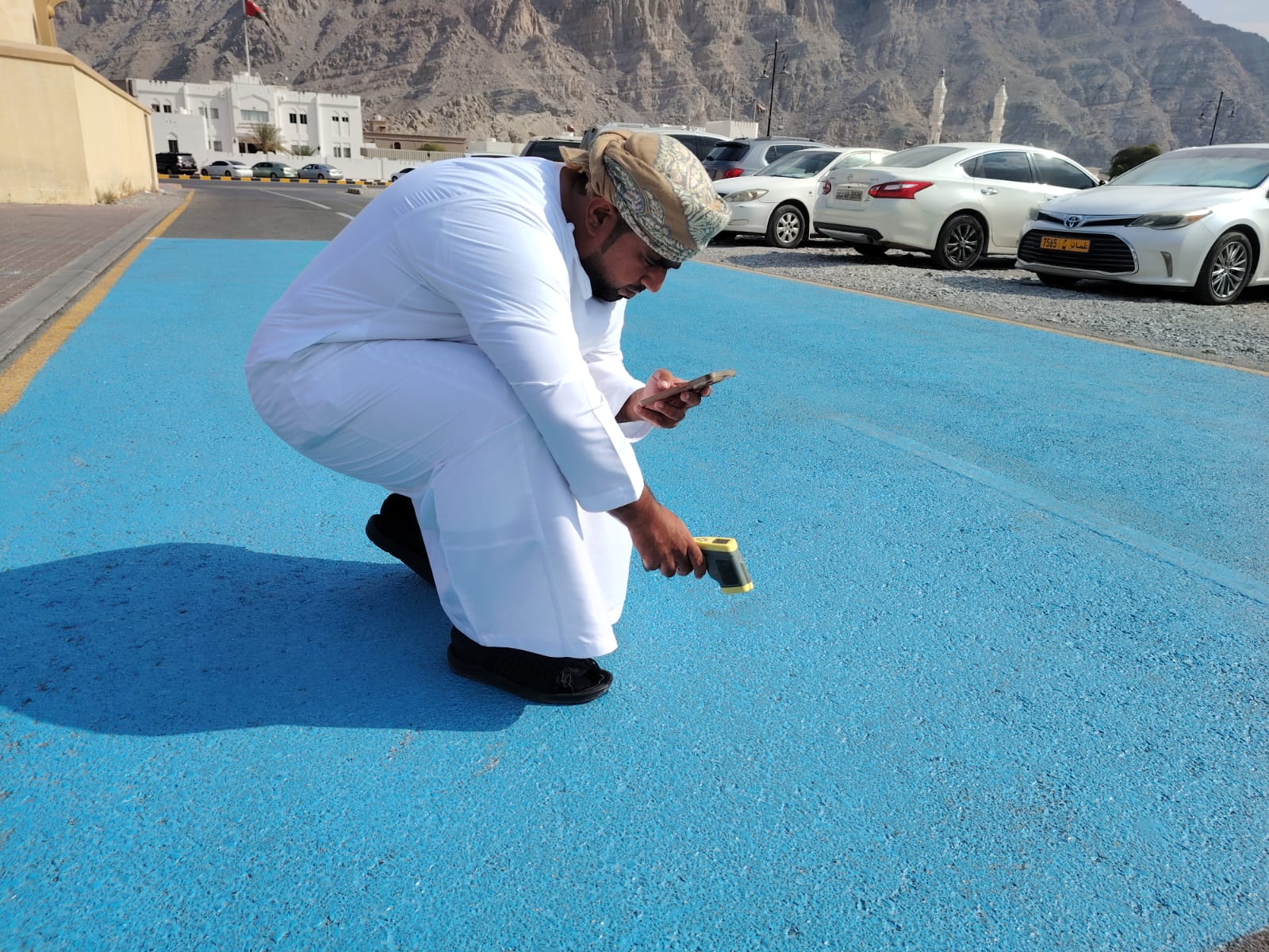 Person taking surface temperature of blue road.
