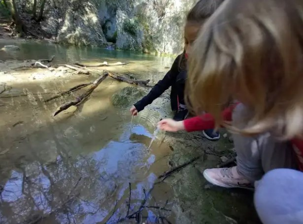 Two children taking water samples from shallow water.