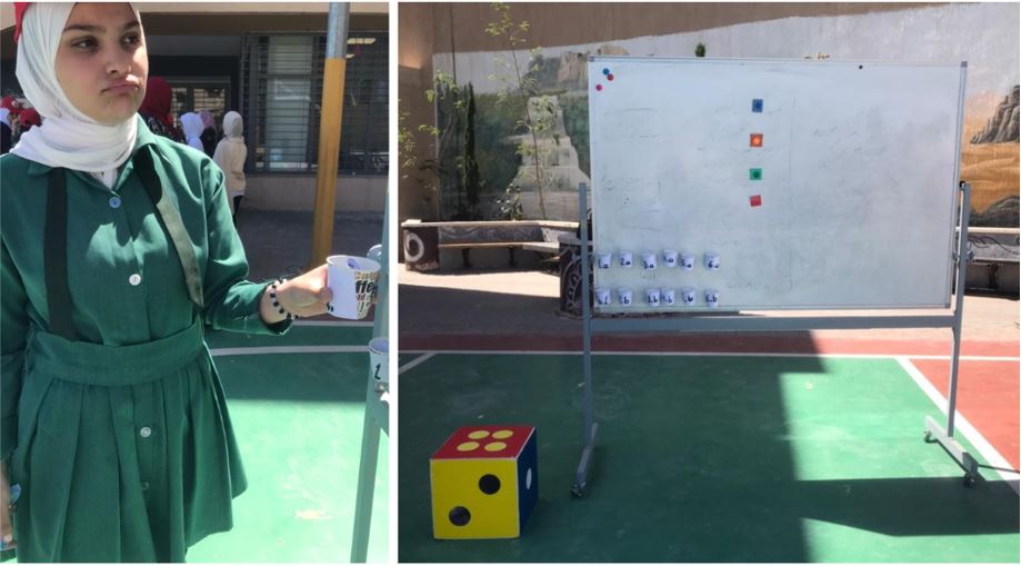 Student playing game with cups, dice, and a whiteboard.