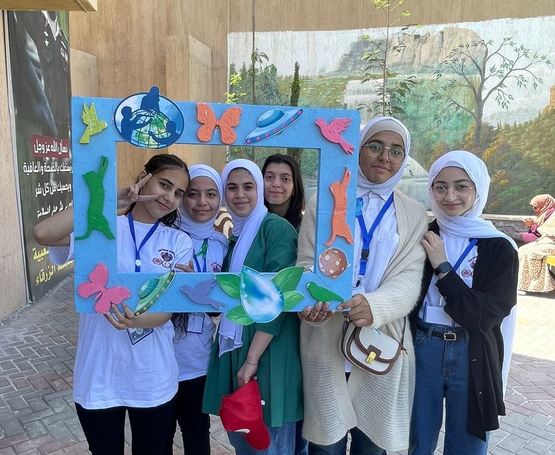 Students posing behind decorated frame.