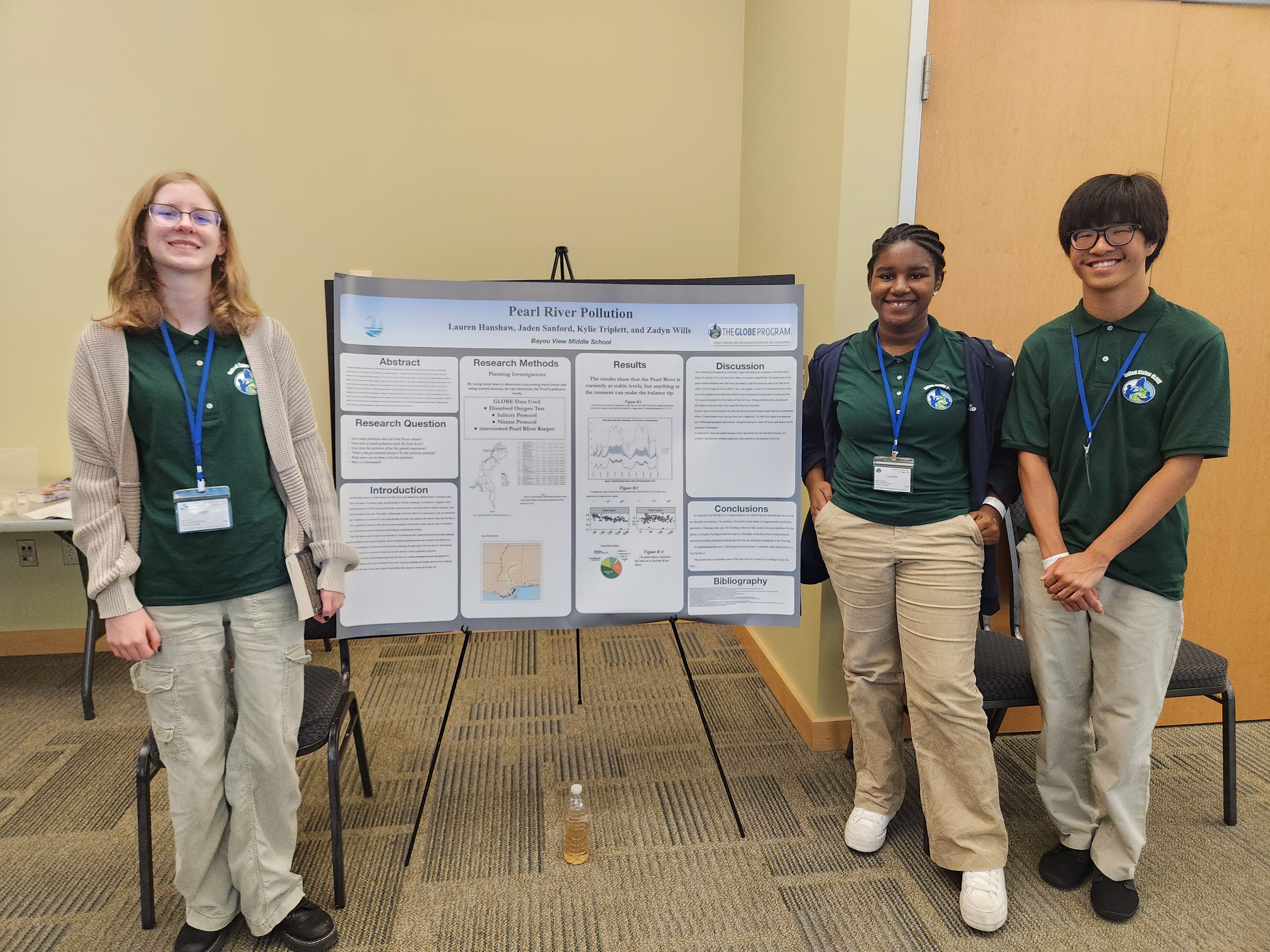 Three students standing by poster displaying their research.