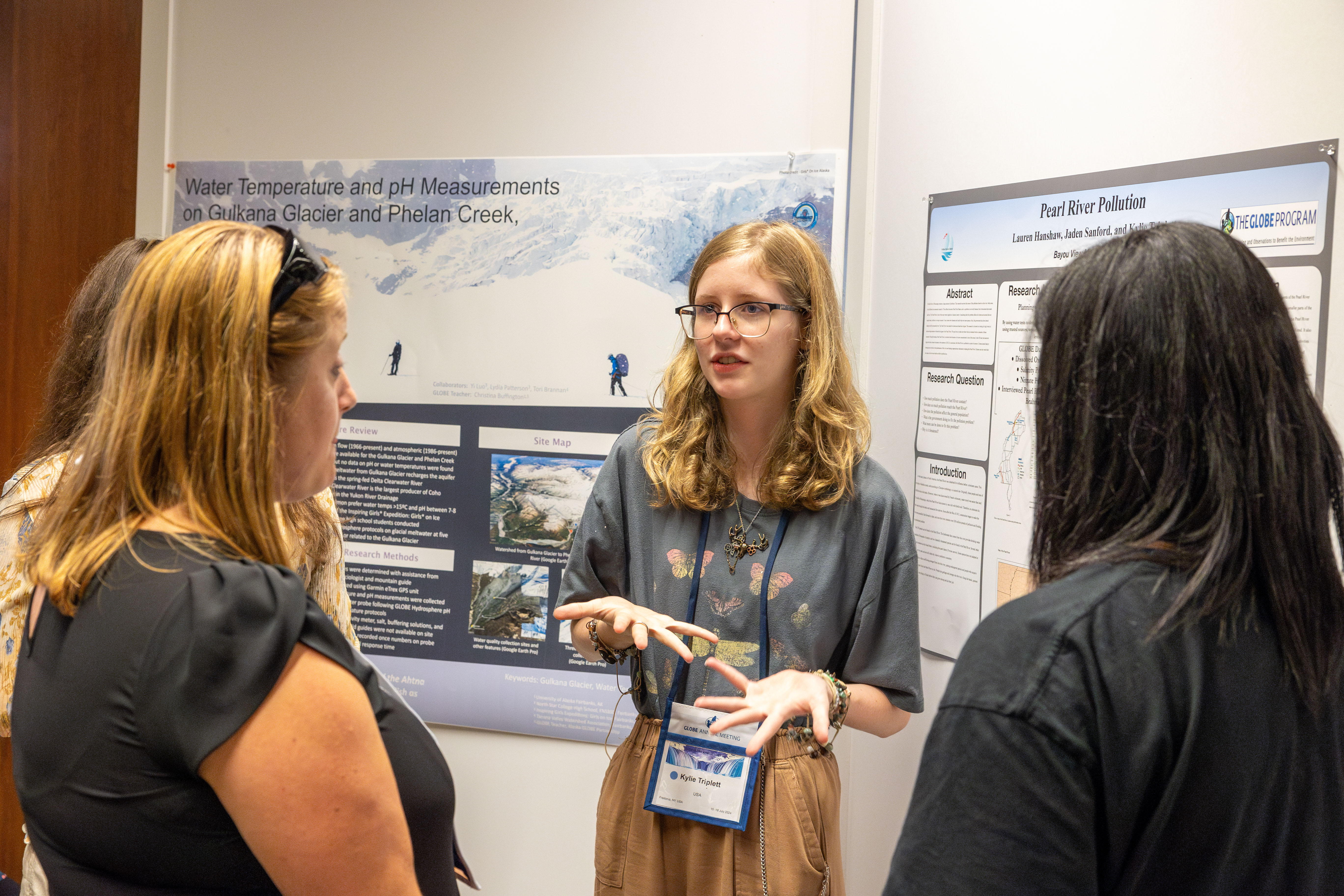 Student sharing research with poster in the background.