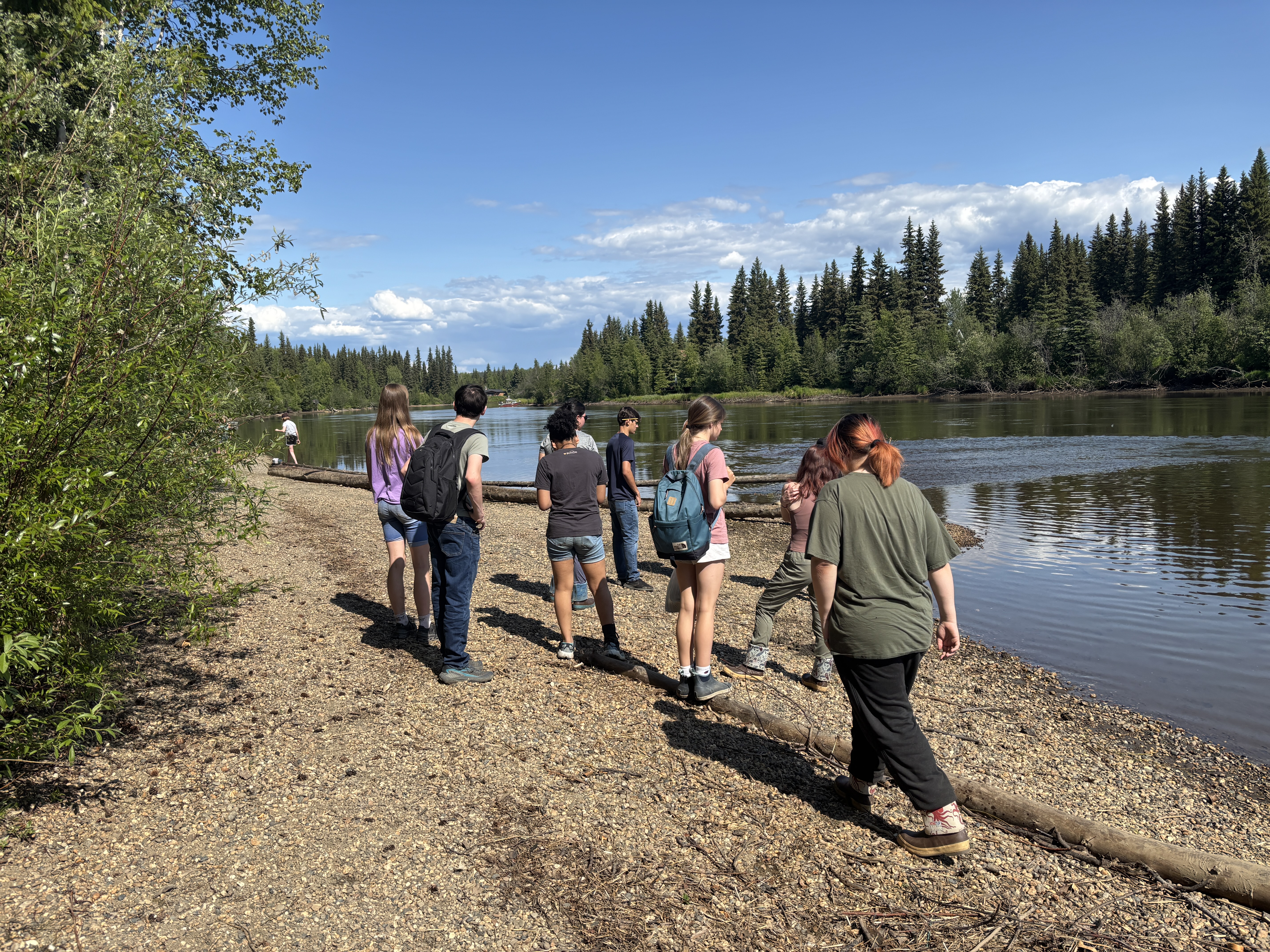 A group of people walking on a rocky shore near a body of water