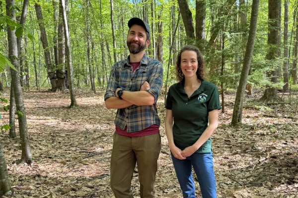 Two people pose for picture in the woods.