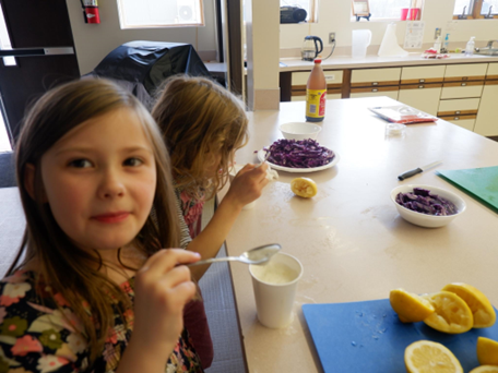 Kids working with lemons and vegetables.