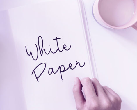 Photo of a hand resting against a piece of paper that reads, "White Paper"