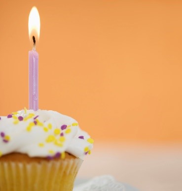 A photo of a cupcake with an anniversary candle lit on top