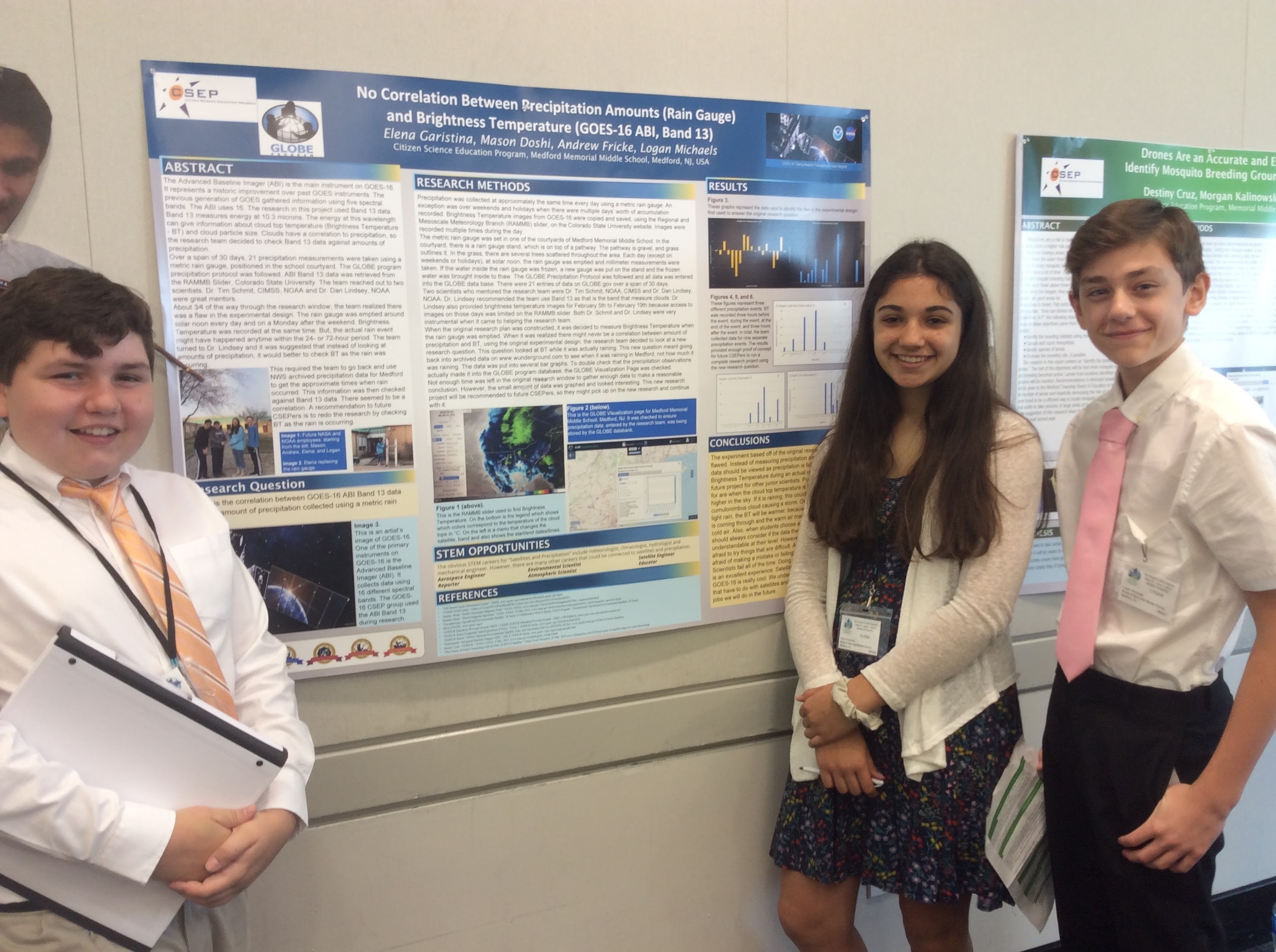 Three students present a board featuring their research.