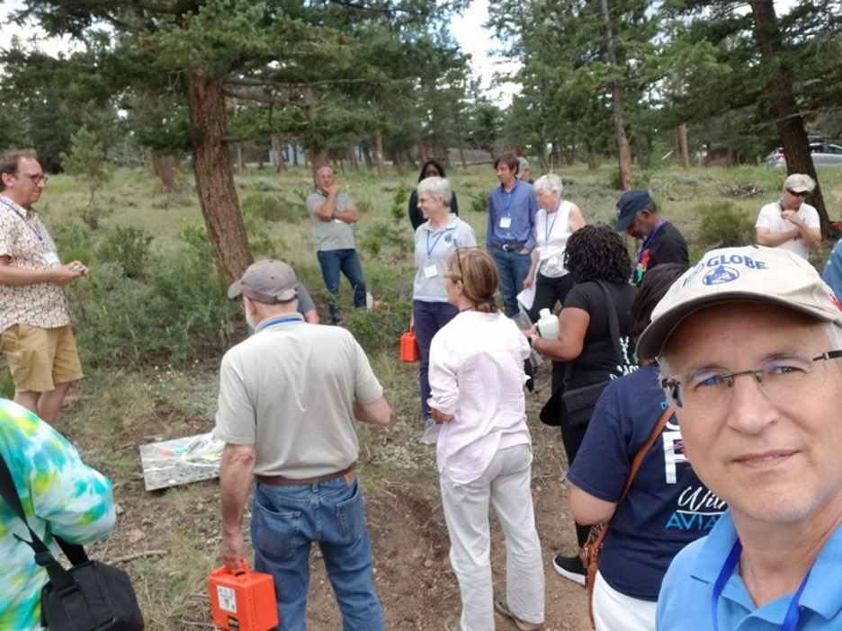attendees standing in a circle to participate in a soil investigation, with Kevin Czajkowski in the foreground