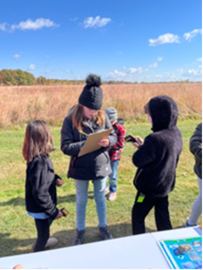 Students students holding infrared thermometers to measure surface temperature share their readings with another student holding a clipboard 