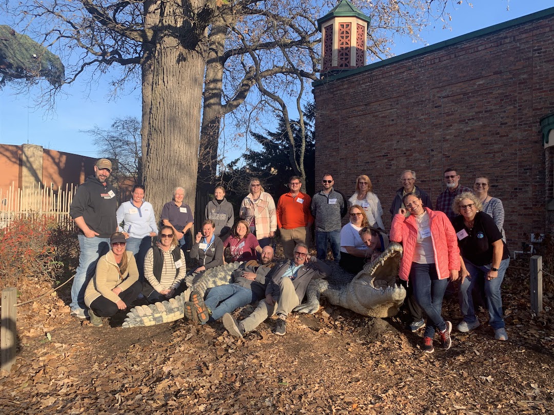 21 participants and one large crocodile statue pose at the Toledo Zoo