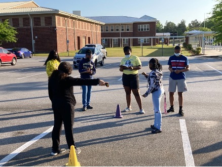 Students use infrared thermometers to measure surface temperature in a parking lot