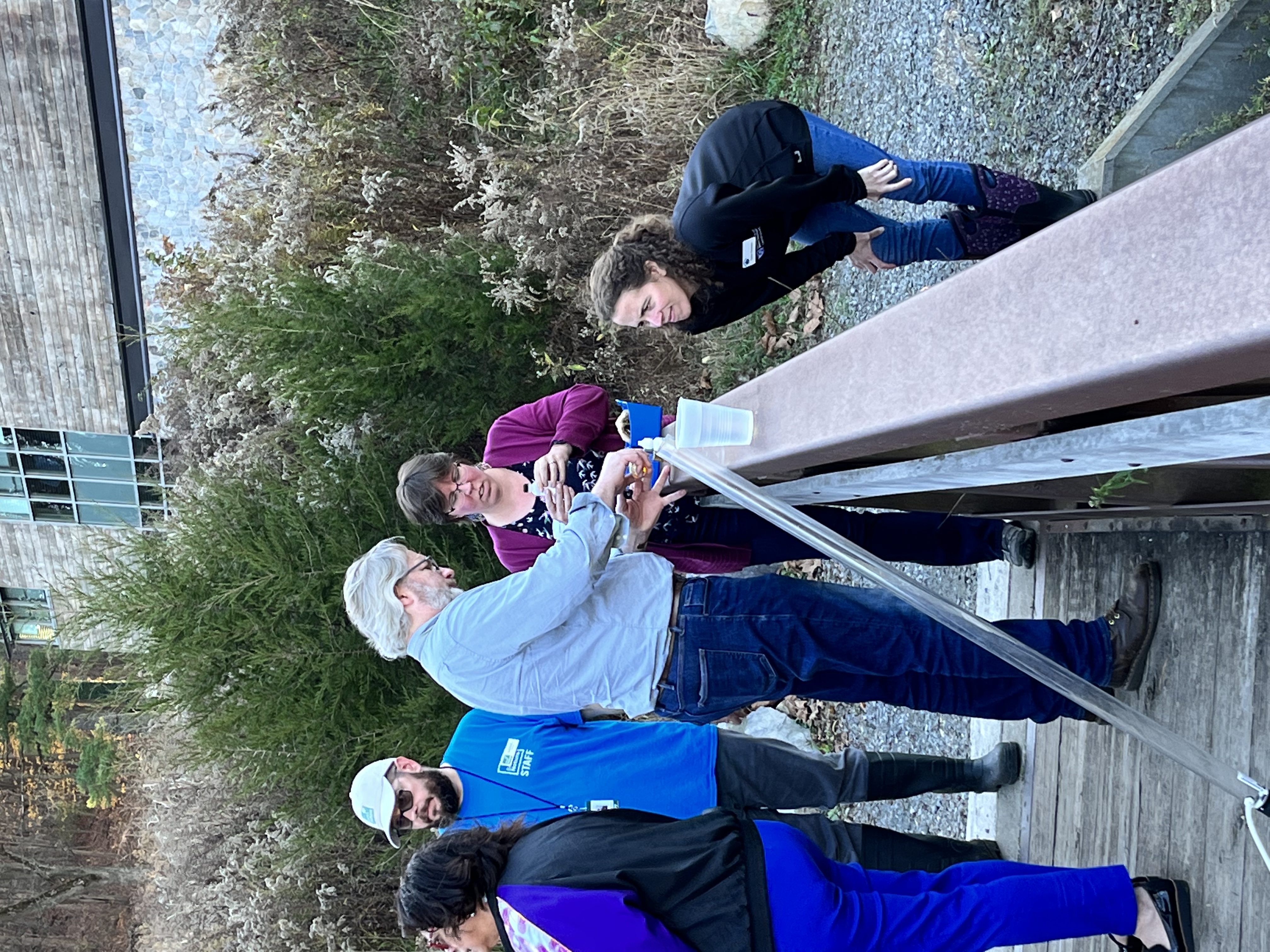 Three participants measure water quality using a kit