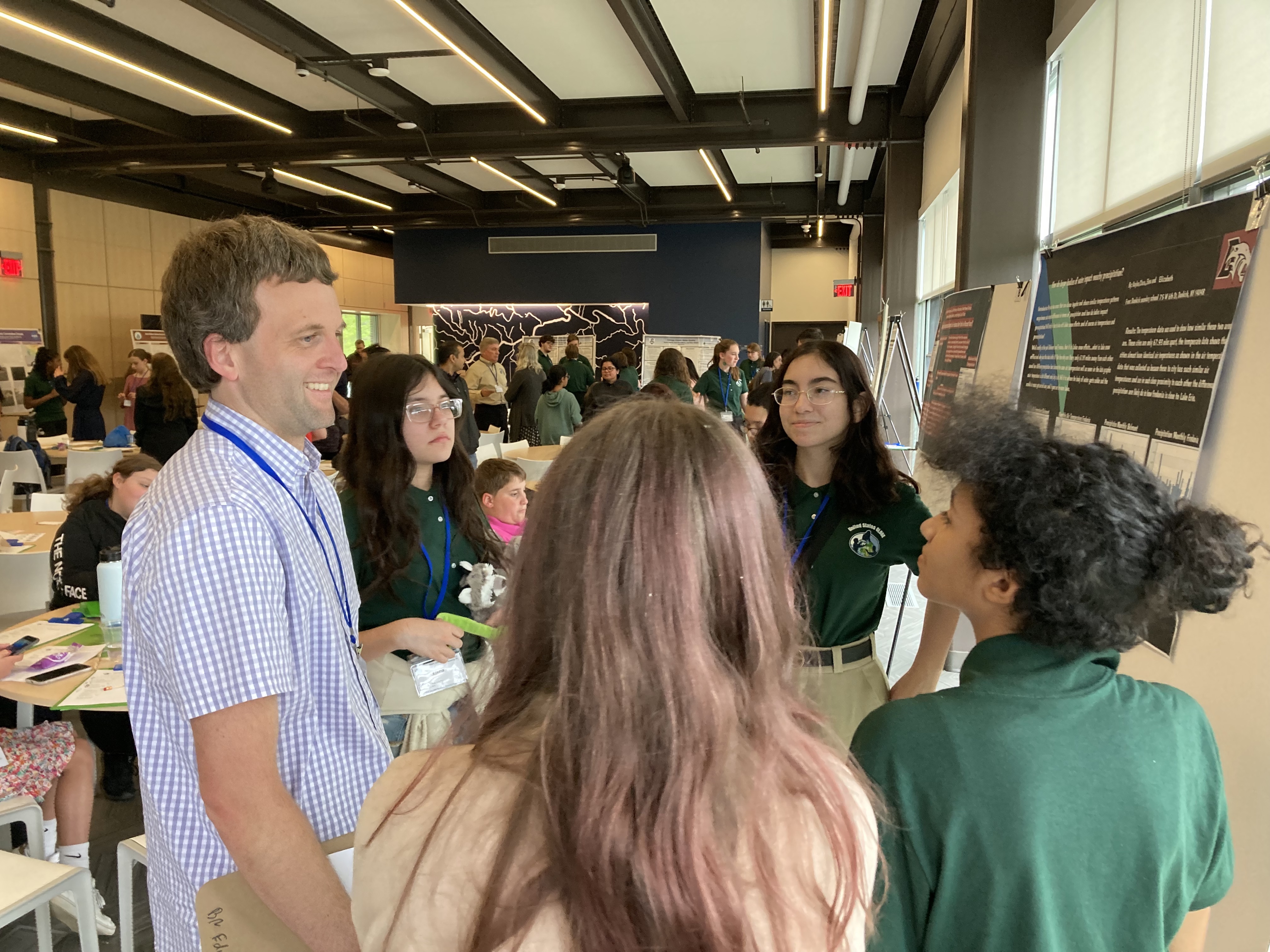 Students discuss their research poster with a scientist at the Northeast & Mid-Atlantic SRS.