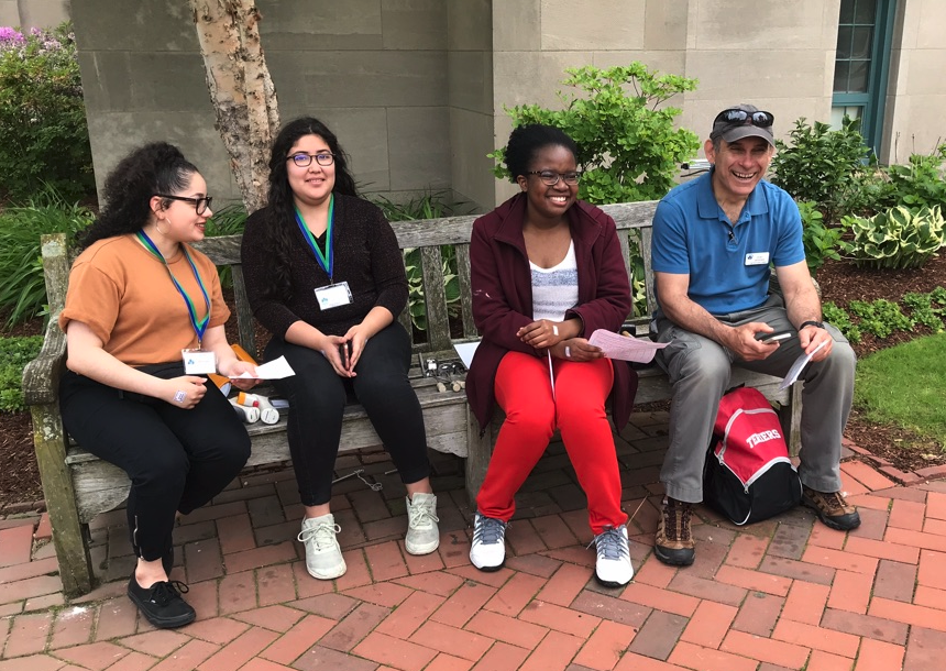 Four educators sit on a bench smiling