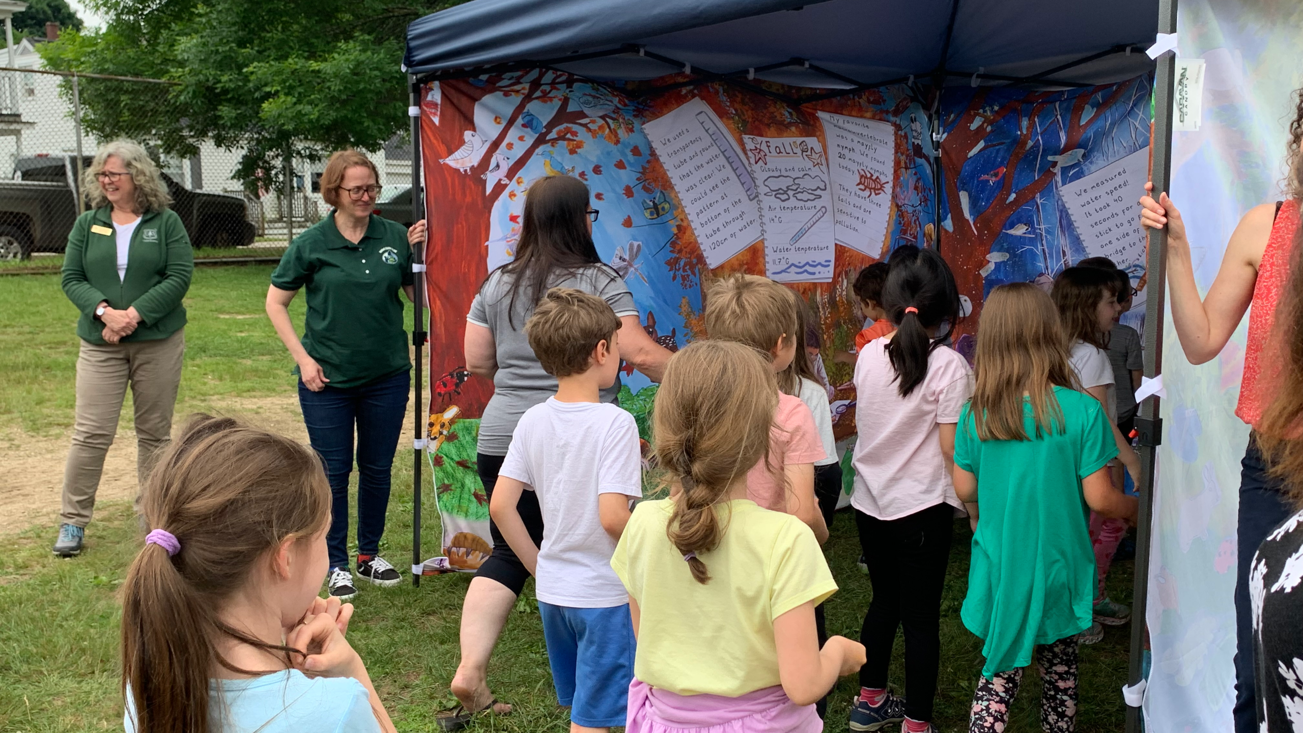 students stand in the New Hampshire Water Tent to see the artwork from their peers