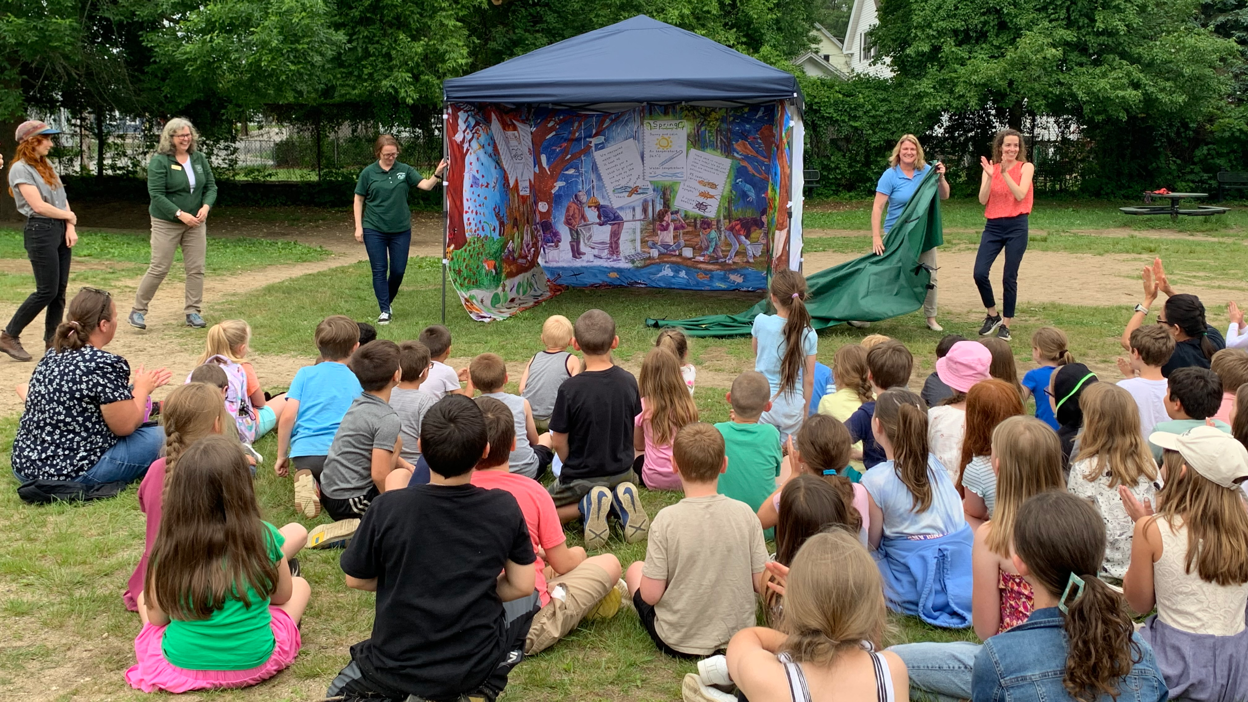 students watch as a curtain is pulled away to reveal the New Hampshire Water Tent