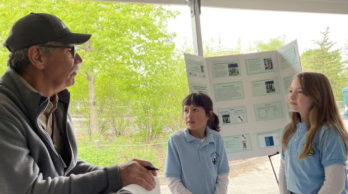 students listen to a STEM professional as they present research at the Toledo Zoo student research symposium