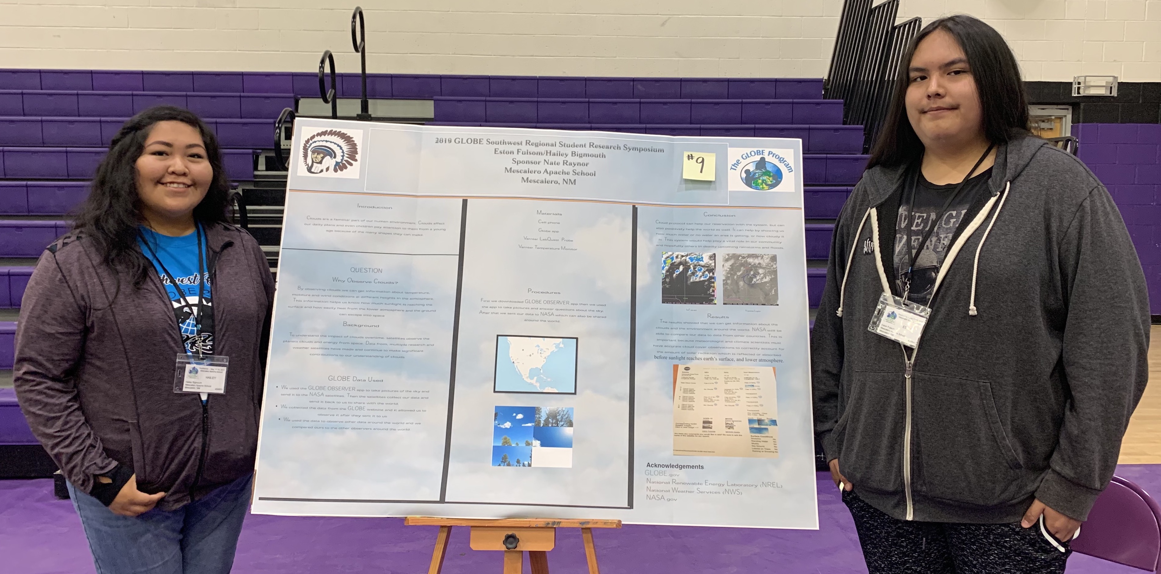 two students from the Mescalero Apache School standing on either side of a poster board with their project on it.