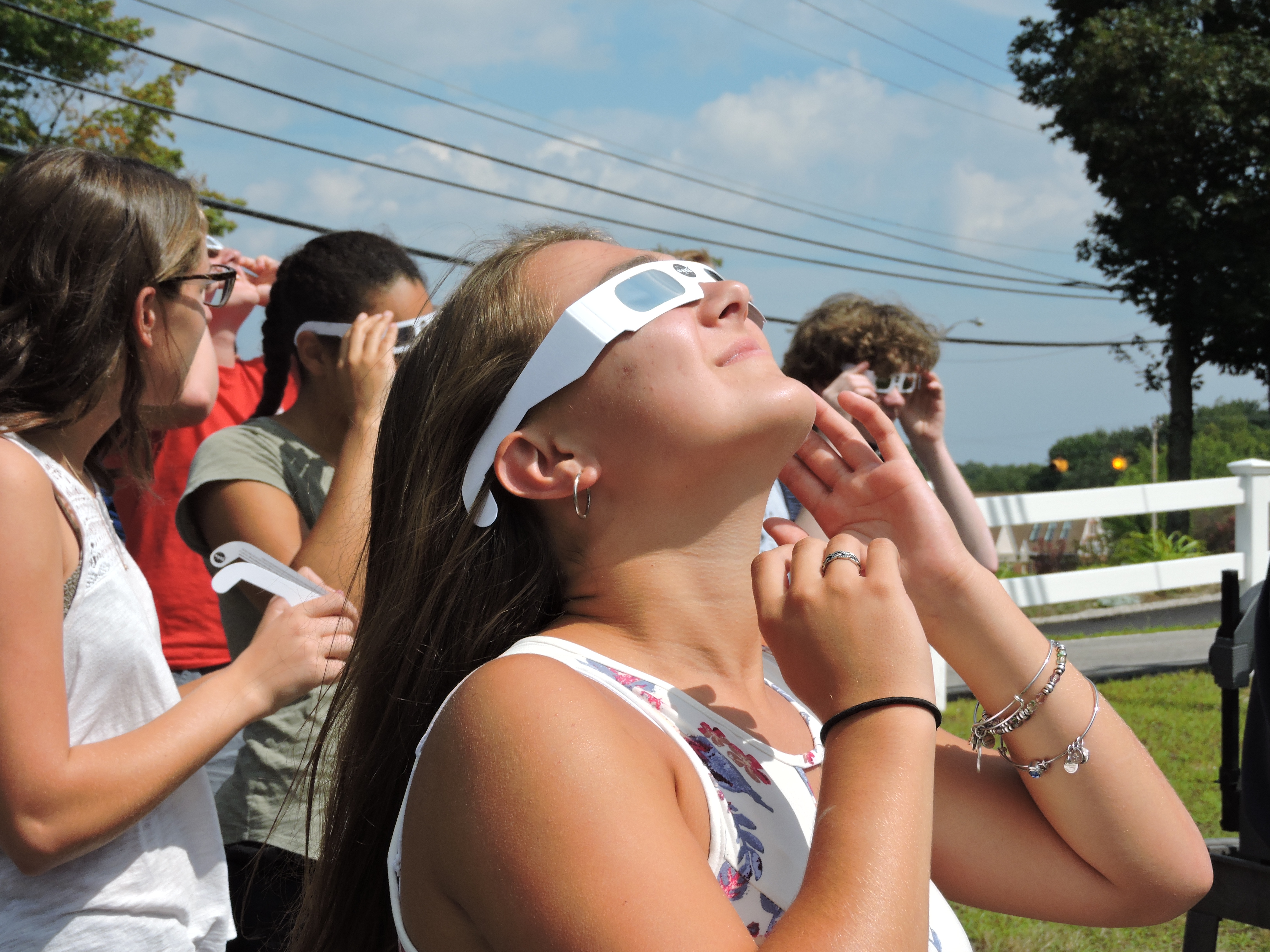 young female student looking up through eclipse glasses