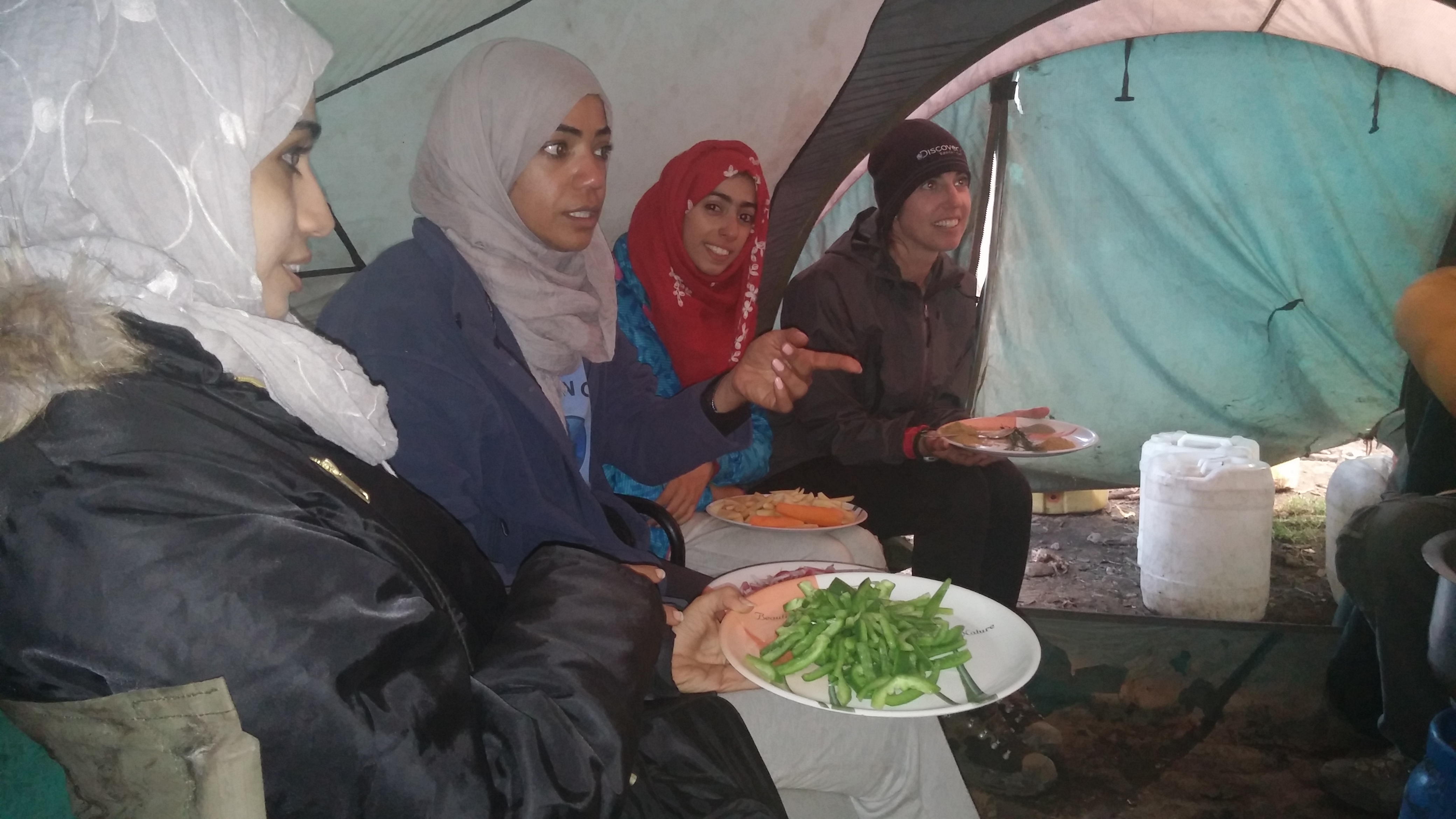 Several women sit with food on plates and bowls.