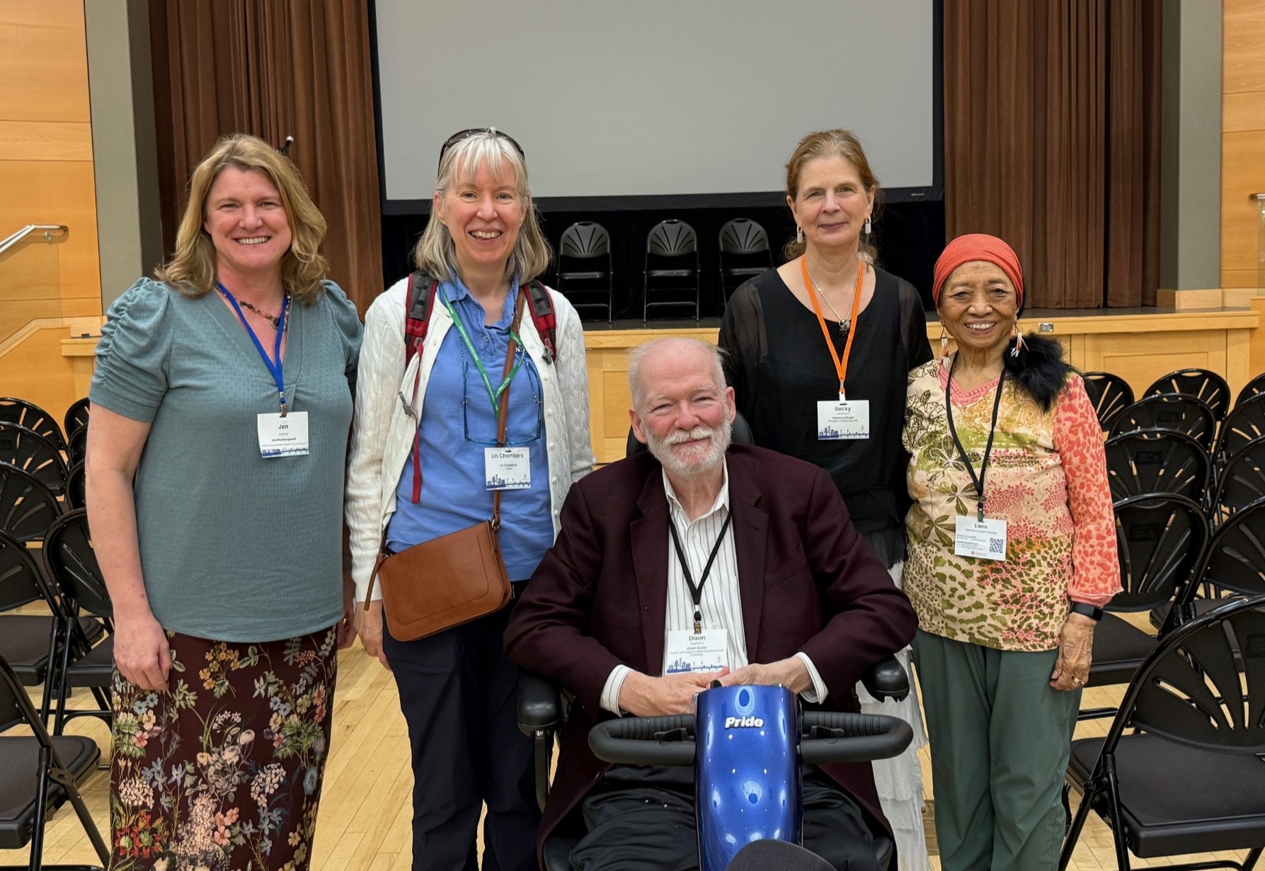 Five people posing for picture in an auditorium.