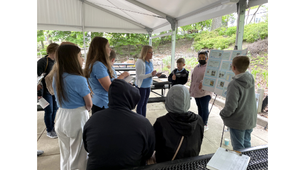   Students and teachers looking on at a poster presentation