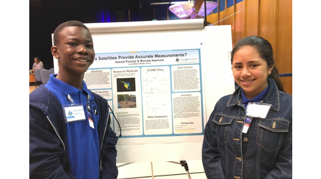   Two students smiling in front of their poster presentation