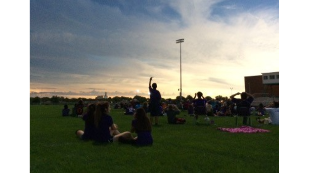   Students in a school soccer field observing a sunset