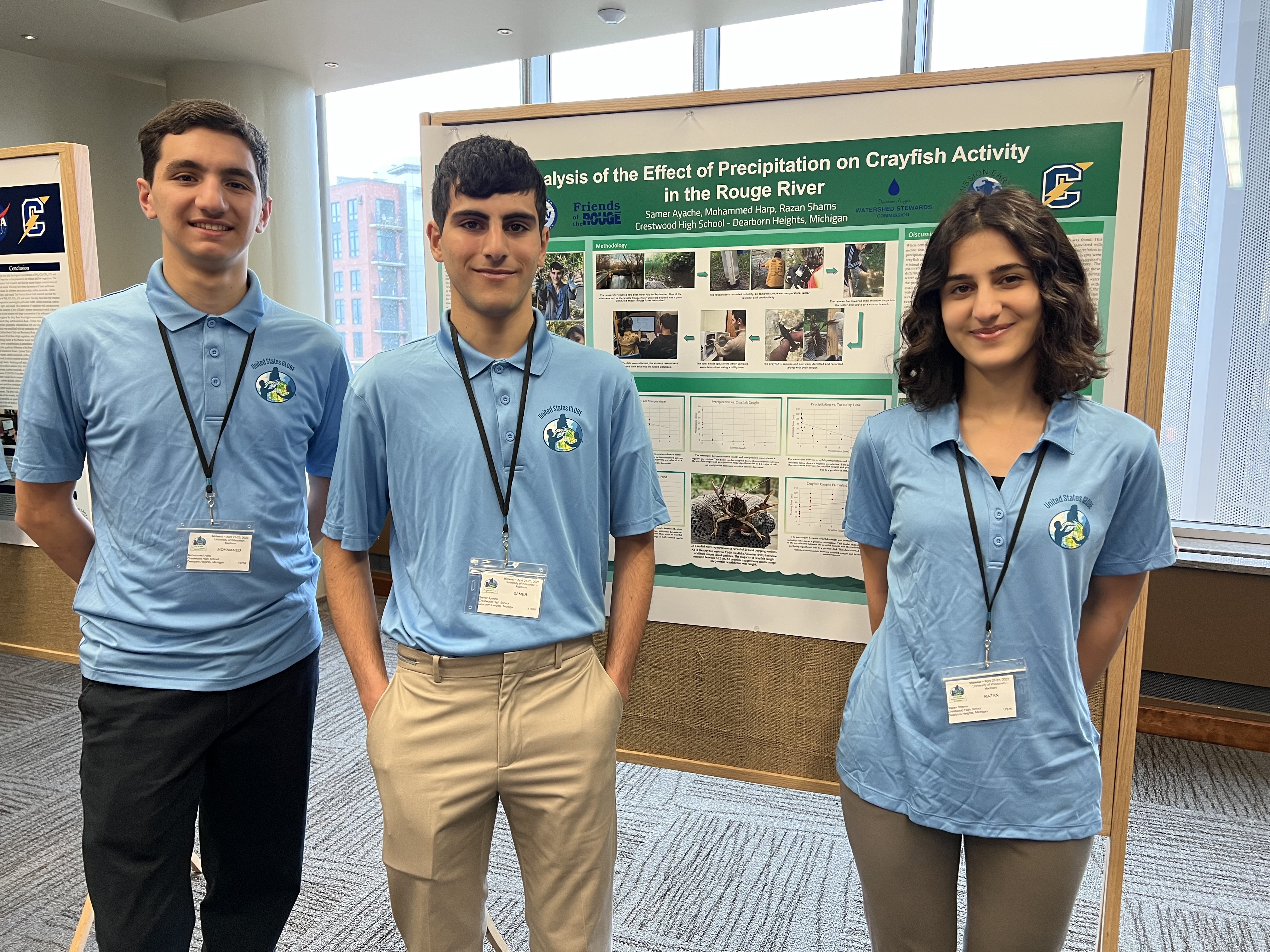 Three students stand in front of their SRS poster   