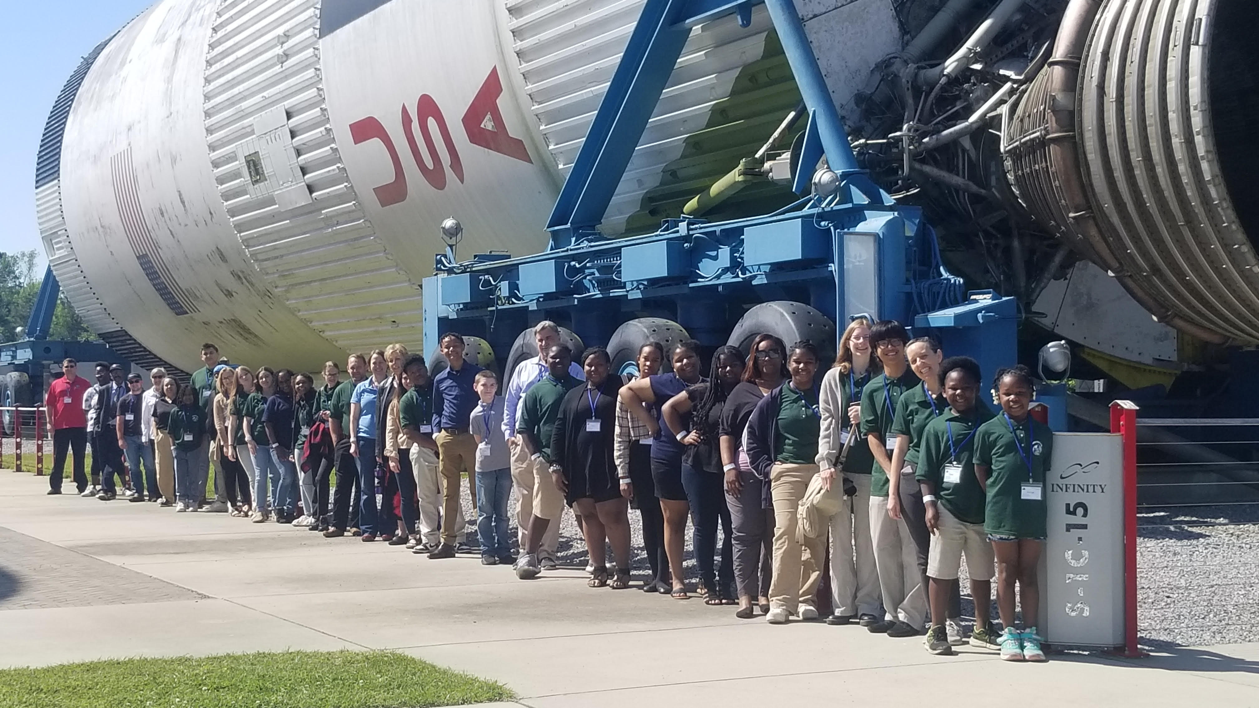 participants at the 2024 U.S. GLOBE Southeast Student Research Symposium stand in front of the Apollo Saturn V rocket at the INFINITY Science Center in Pearlington, MS