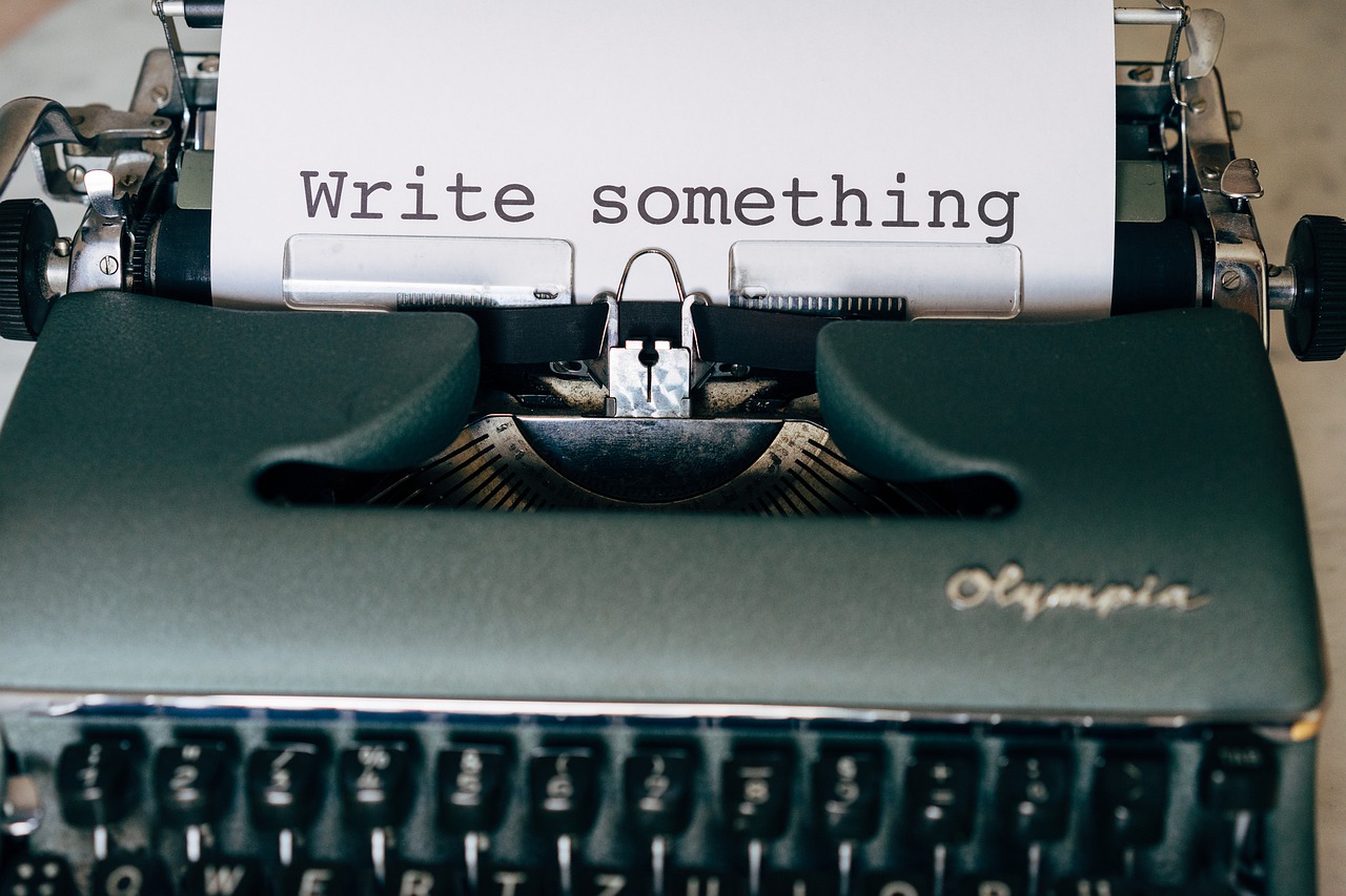 a typewriter with paper that reads "write something"