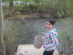 student with bucket near stream