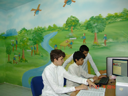 Children on computers in front of a mural