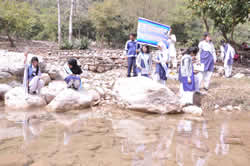 Girls with posters by water.