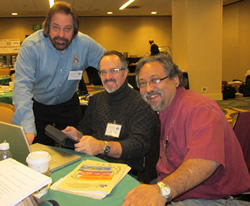 3 men smiling at a table.