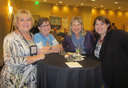 4 women smiling at a table.