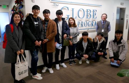 Students and teachers in front of GLOBE sign on a wall.
