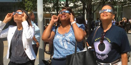 3 women with eclipse glasses.