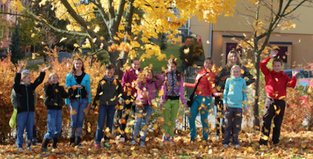 Children throwing yellow leaves into the air. 