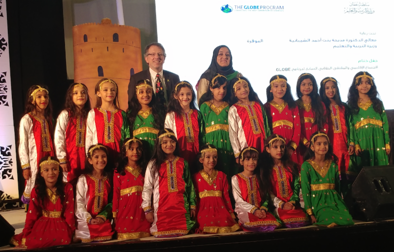 Tony in Oman with school children in red and green/