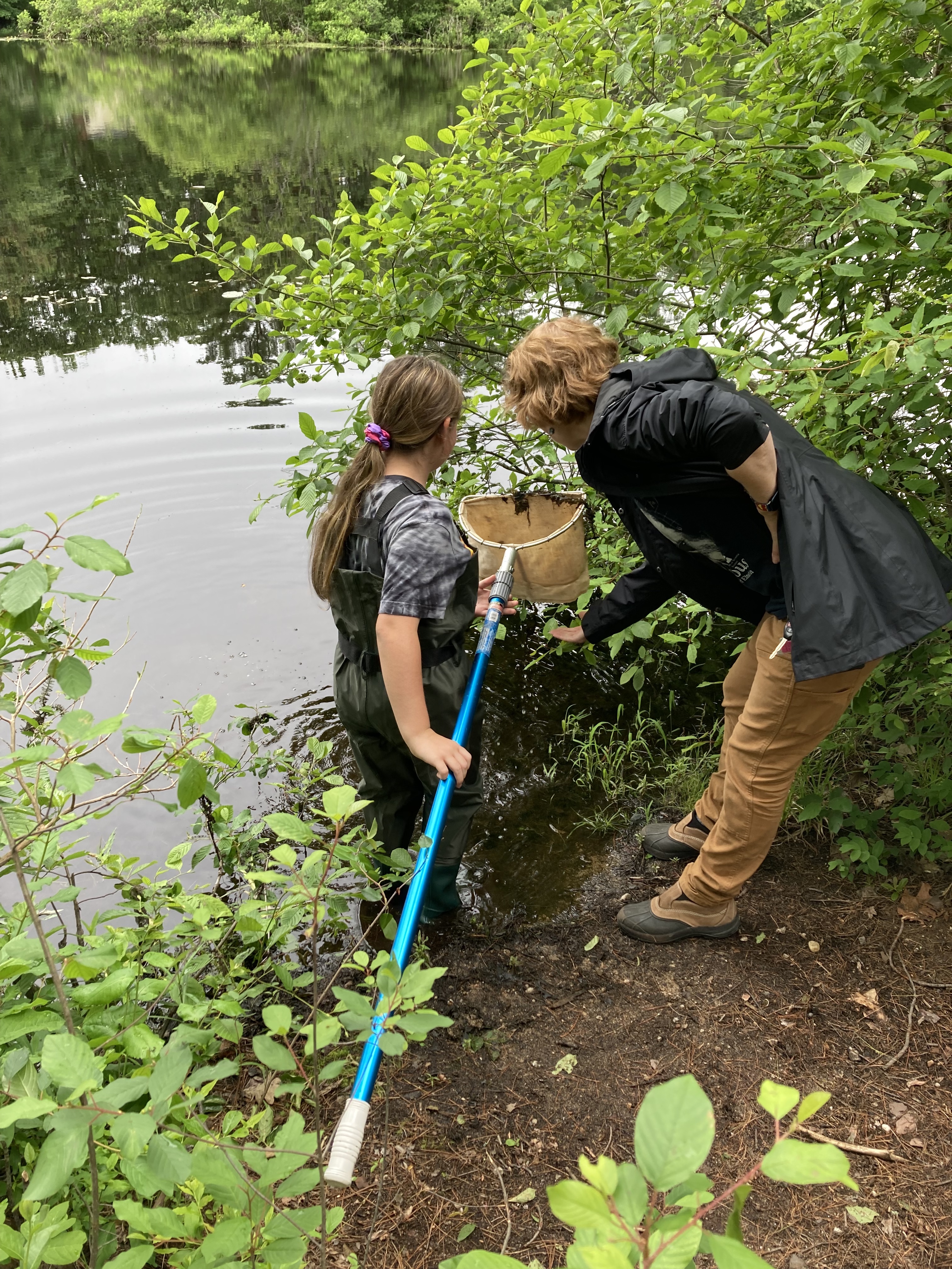 a student and scientist look for macroinvertebrates in a net