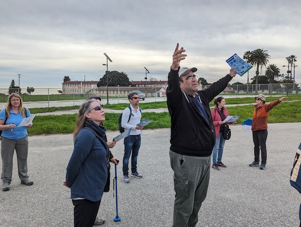 John Olgin stands with his hands up to demonstrate looking at a quarter of the sky when observing clouds