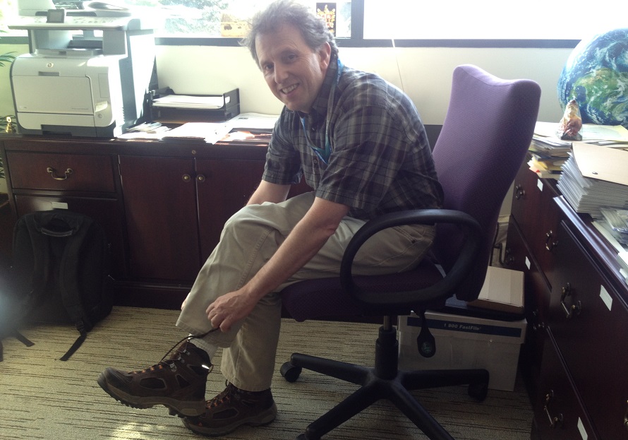 A man ties his shoelaces while sitting in a chair.